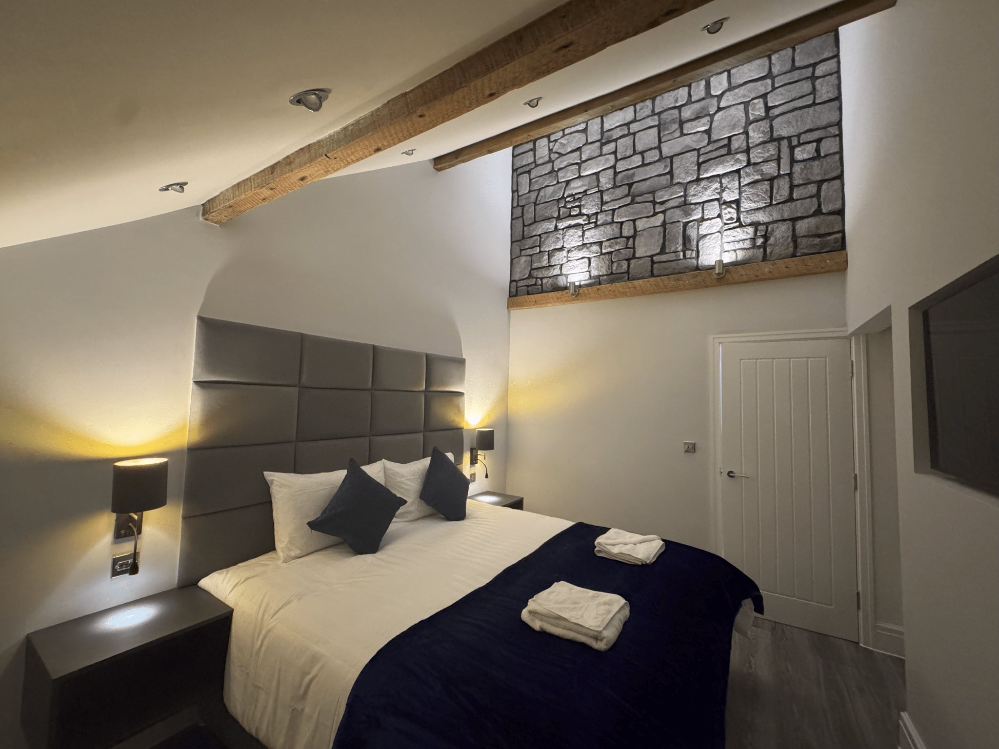 North Apartment bedroom with exposed beams and stone feature wall