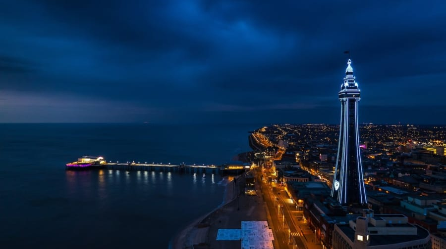 Blackpool Tower lit up at night beside the pier and promenade