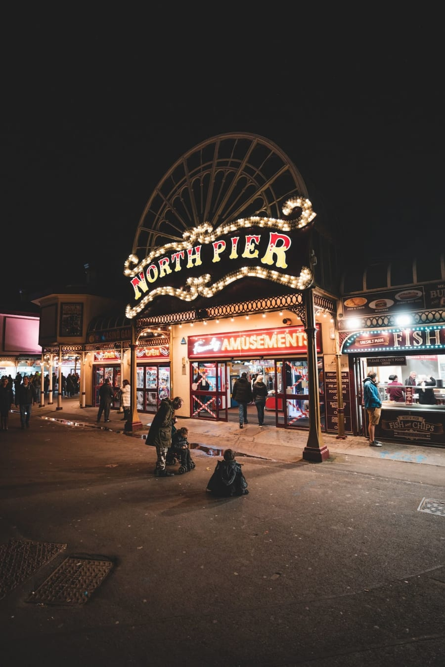 Illuminated North Pier entrance sign at night