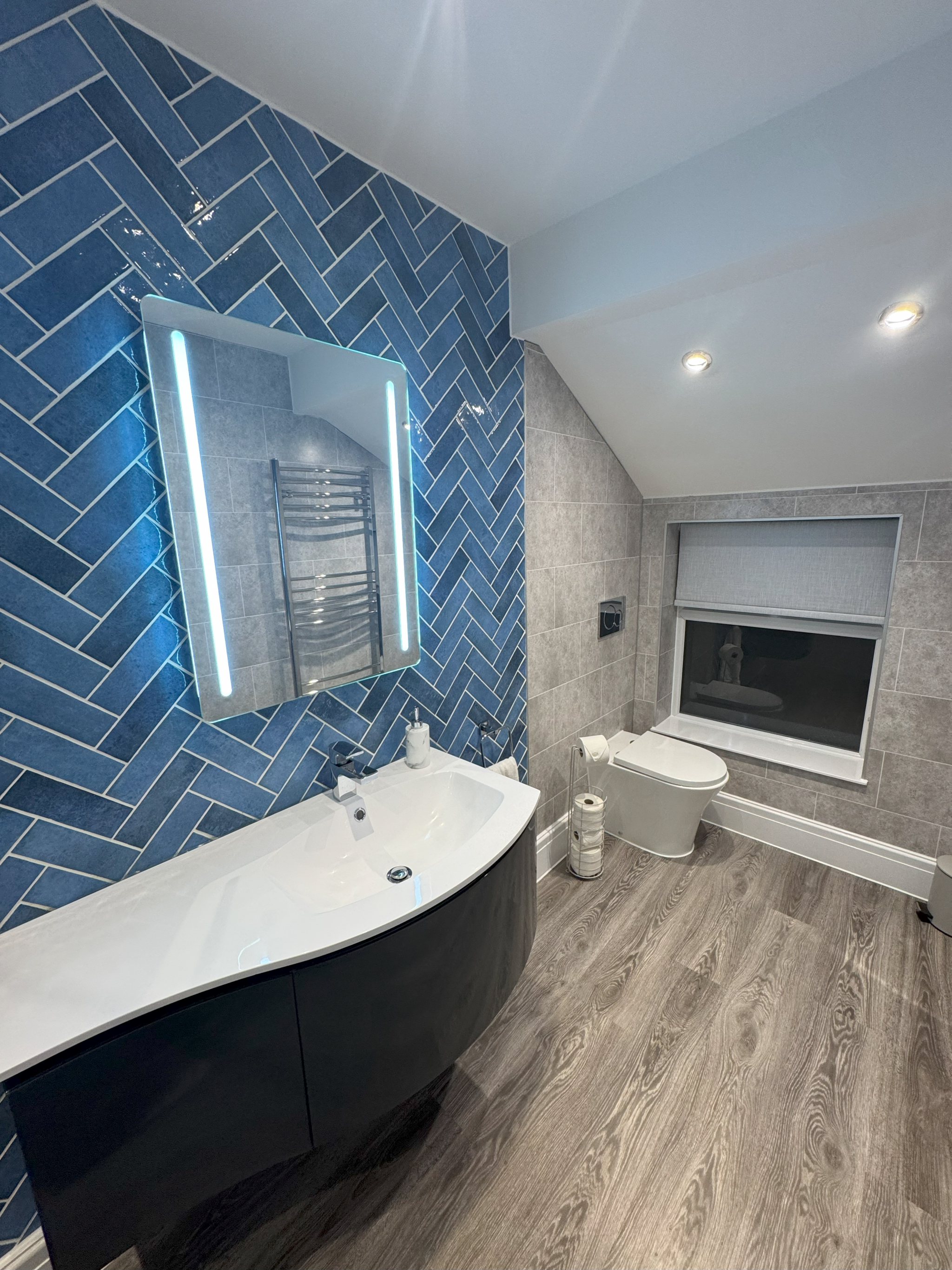 Bathroom with blue herringbone tiles, curved basin and toilet