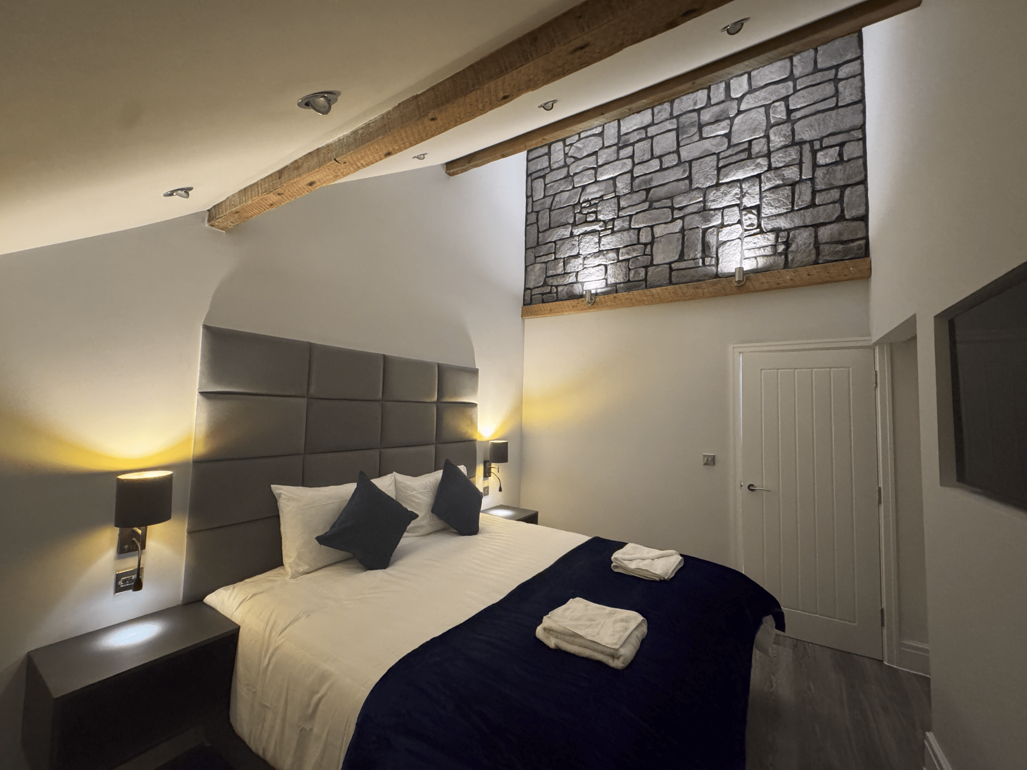 Bedroom with exposed beams and stone feature wall