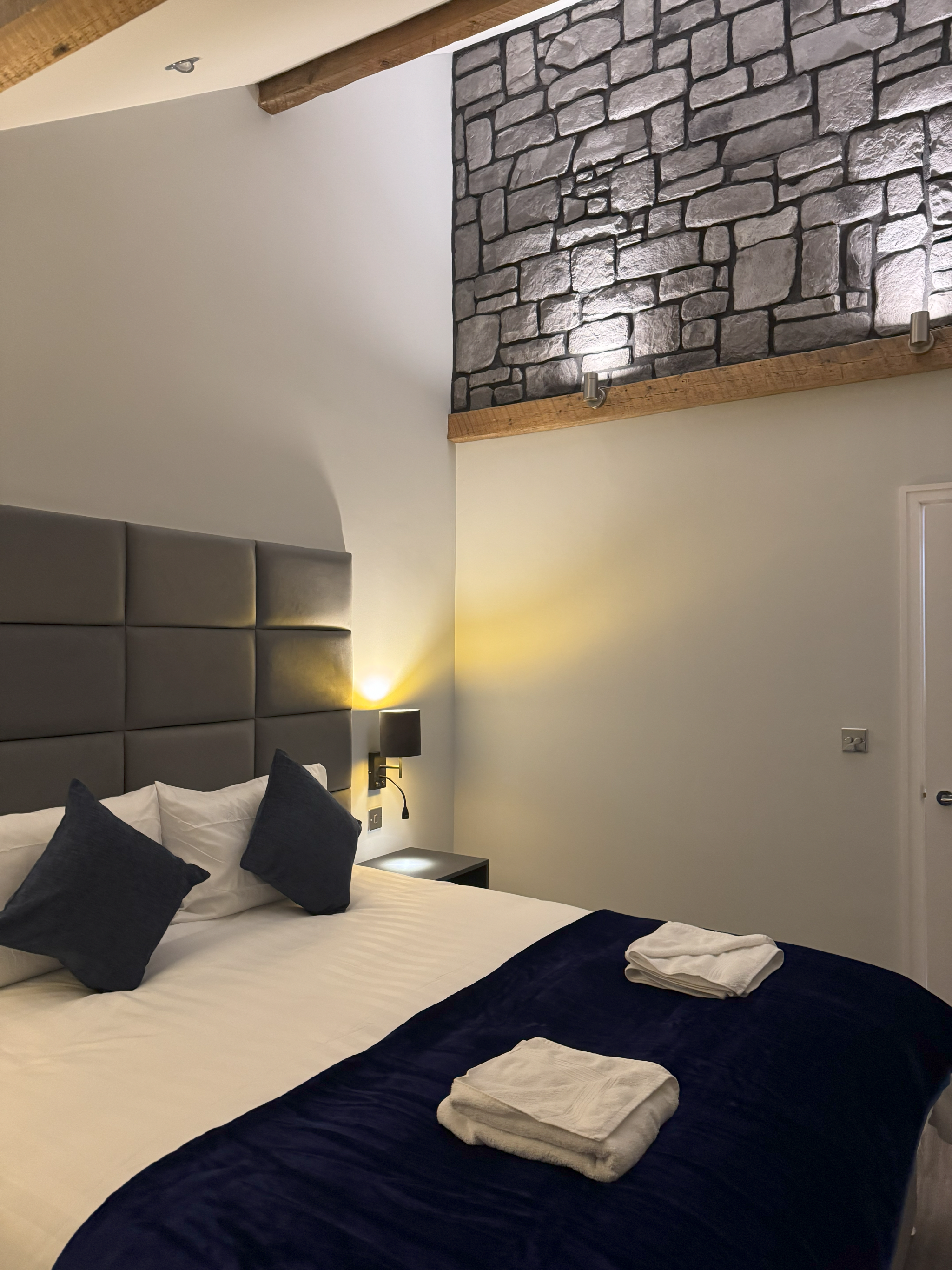 Bed with grey padded headboard and navy cushions