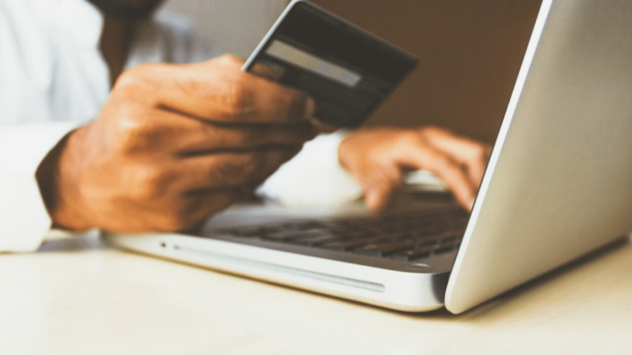 Person holding a bank card while using a laptop
